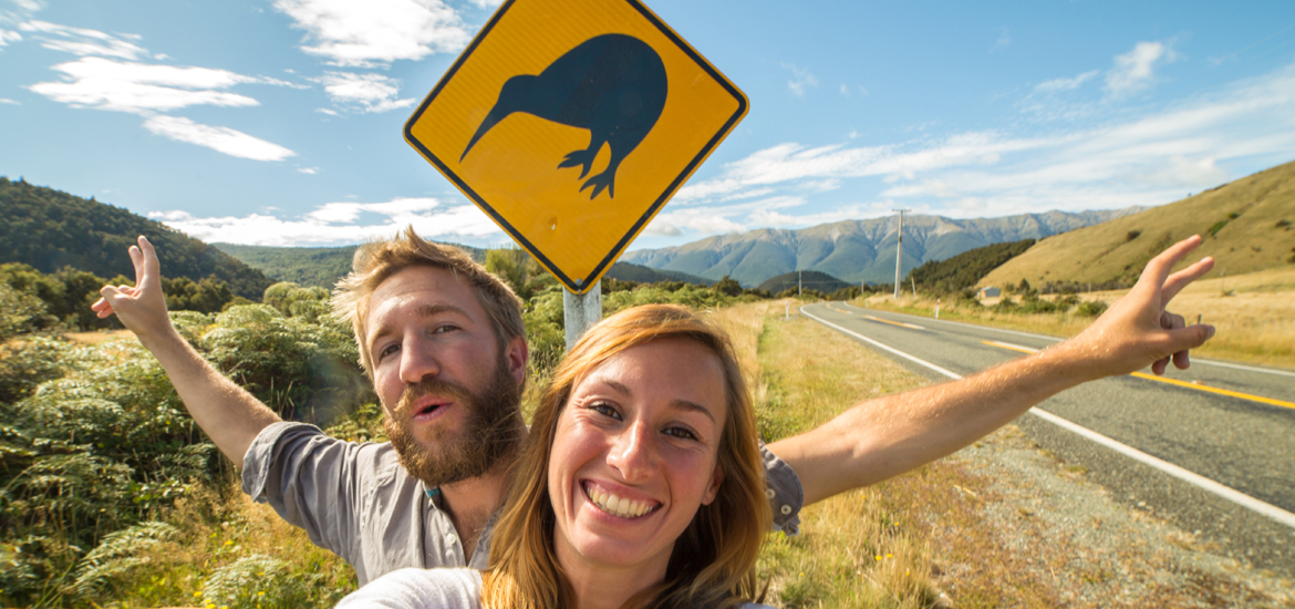 Kiwi couple in front of a kiwi sign